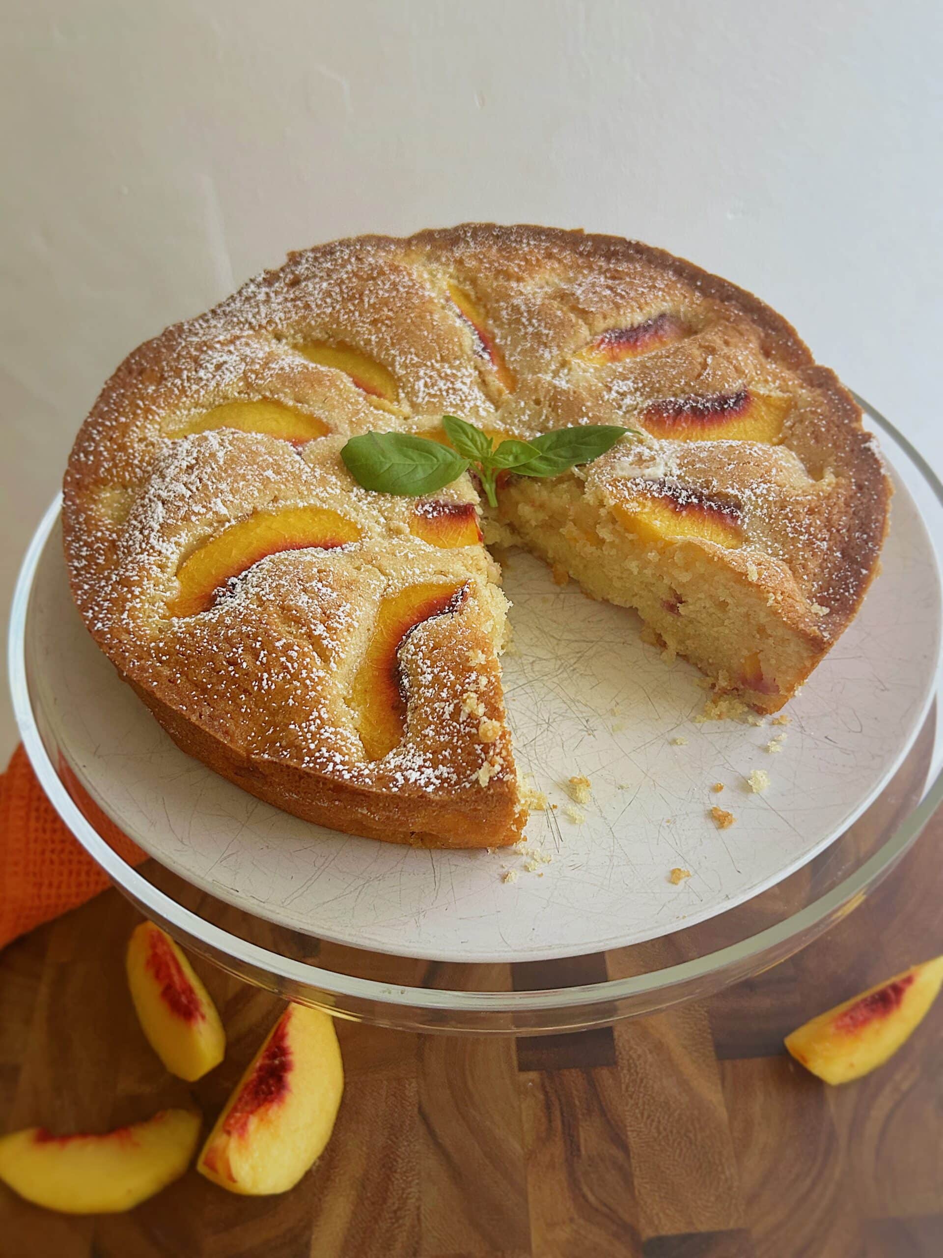 Full fresh peach cake with a slice missing.