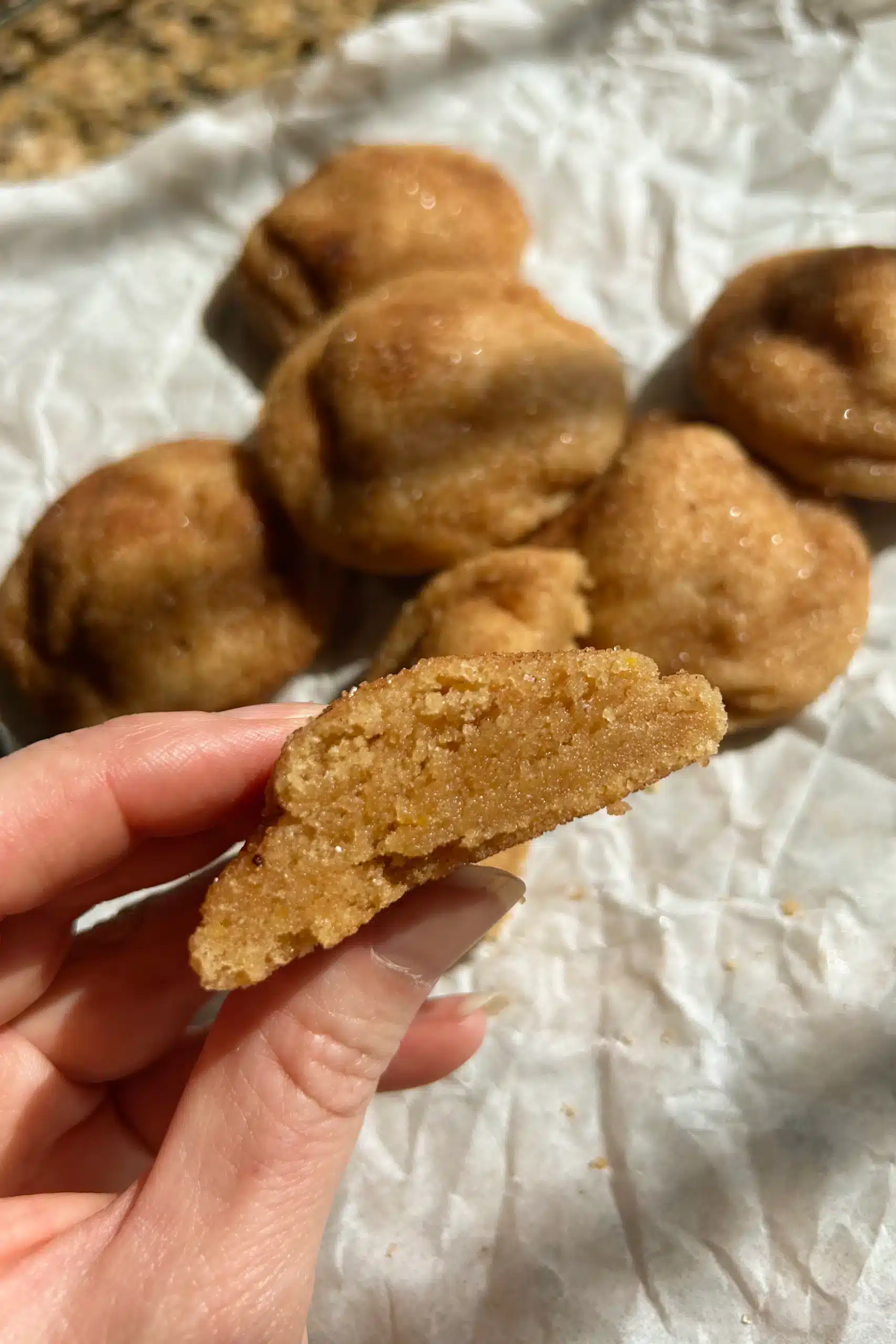 Hand holding half of a brown butter snickerdoodle showing the extra soft center of the cookie.