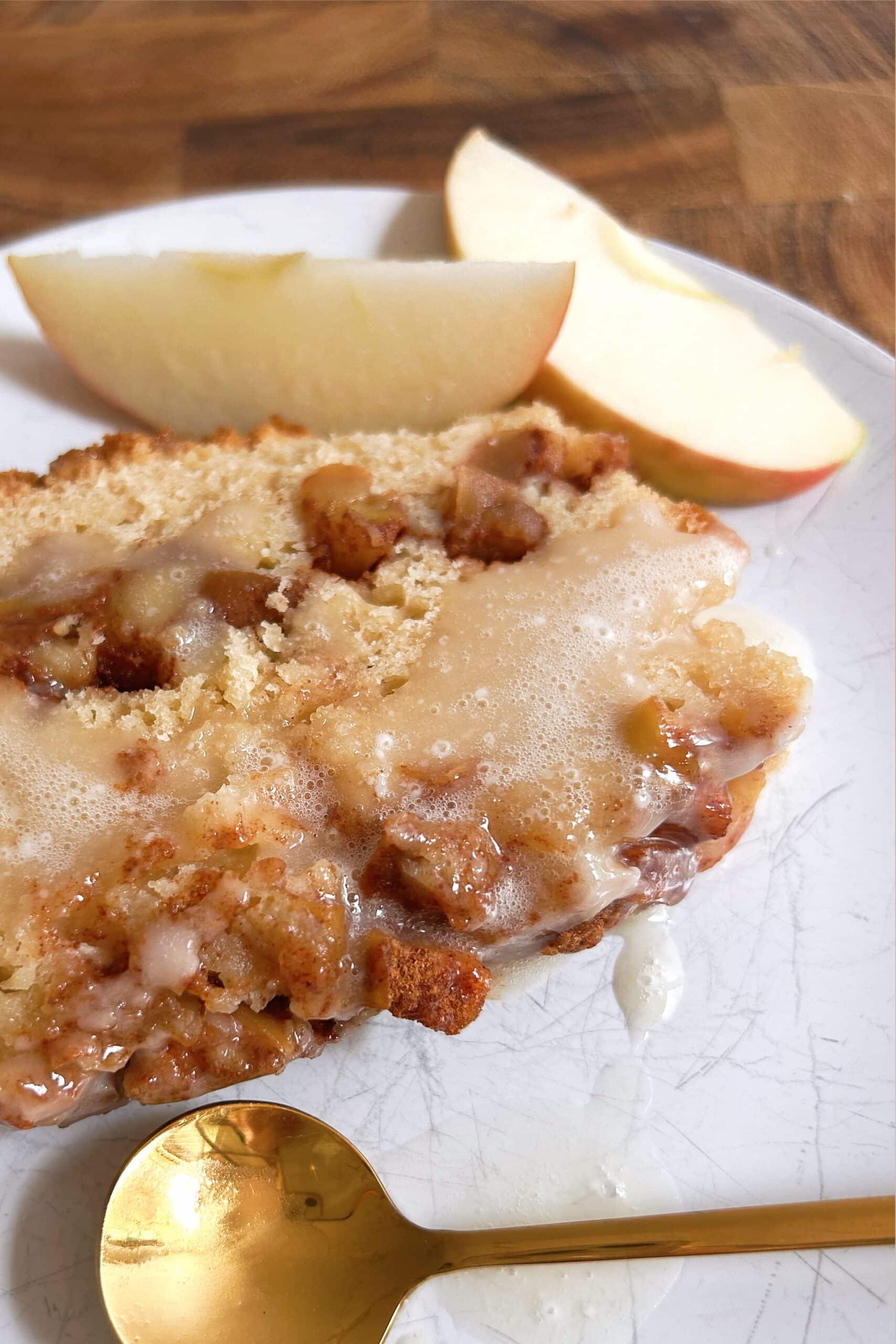 Slice of Brown Butter Apple Fritter Bread drizzled with vanilla glaze.